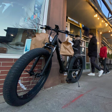 A cargo bike parked outside of a restaurant.